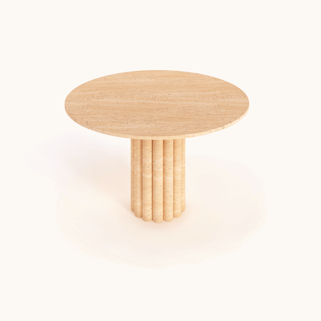 The Classic Round Travertine Dining Table from Travertable showcases a smooth top and unique cylindrical column base, embodying minimalist design. Its light beige hue stands elegantly against a white background.