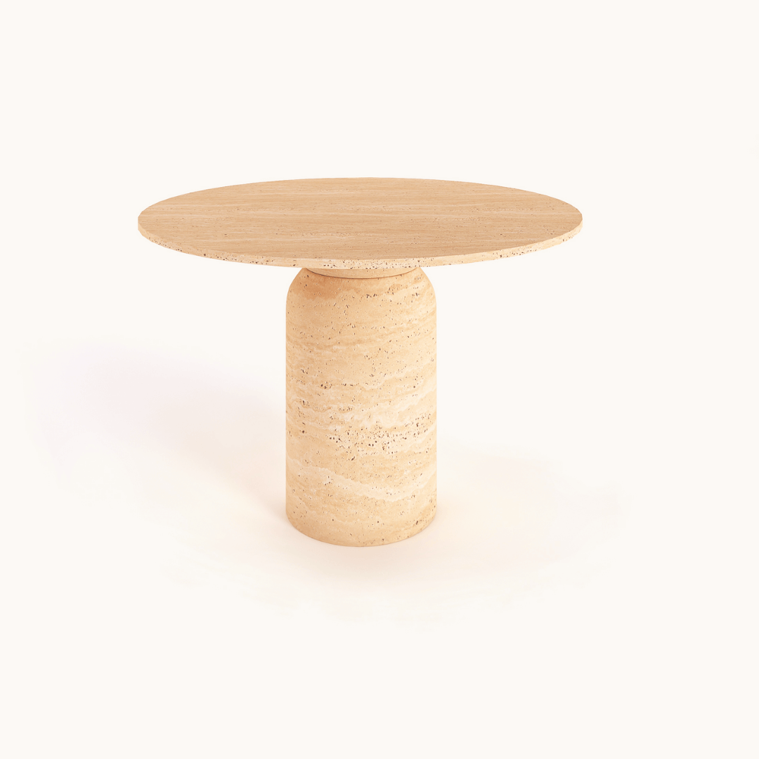 The Classic Round Travertine Dining Table by Travertable features a light wood with a thick cylindrical base, offering a bespoke feel. Its seamless, minimalist, modern design is set against a plain white background.