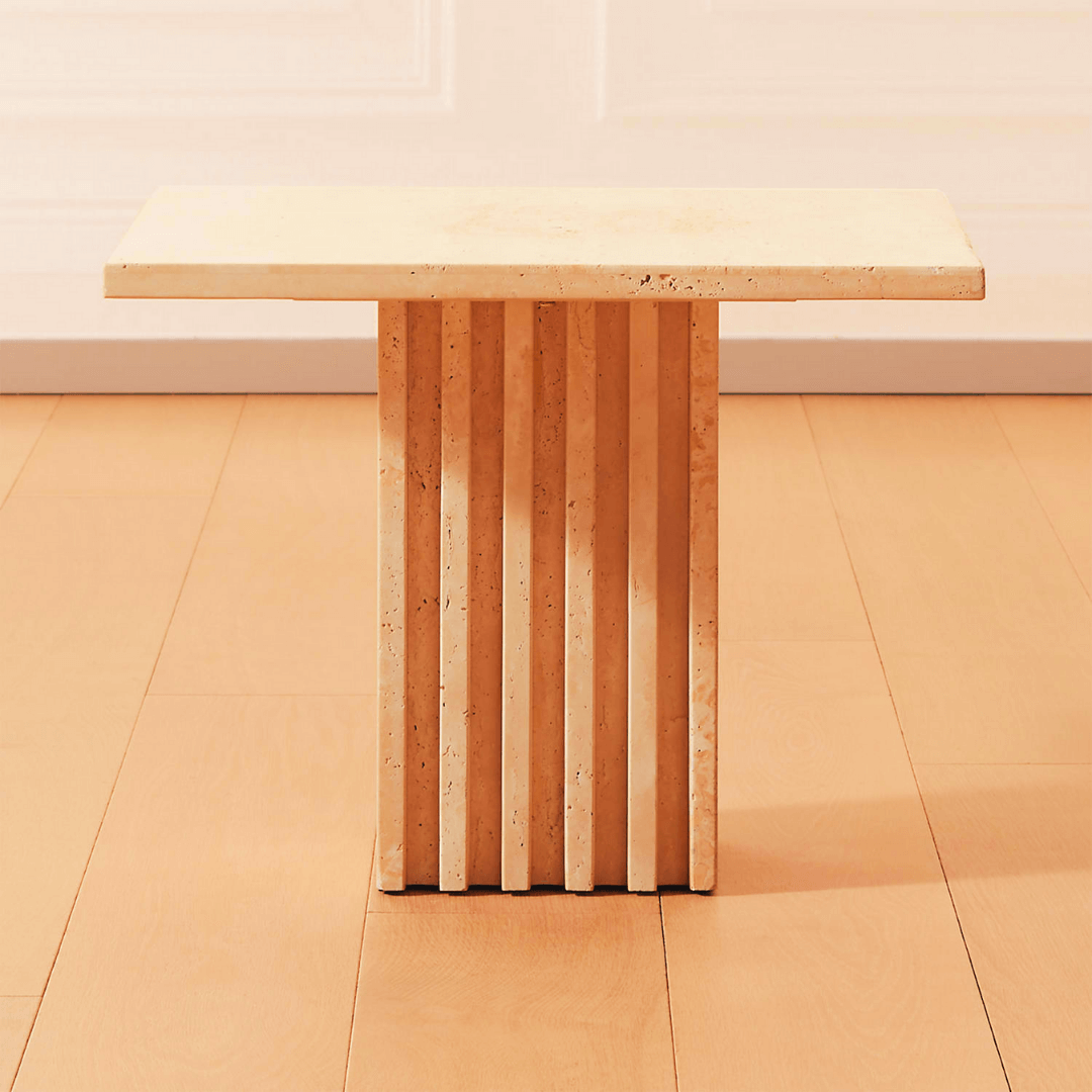 The Harmony Square Travertine Dining Table from Travertable features a light wooden rectangular top and a unique fluted pedestal base, elegantly placed on a warm-toned wood floor.