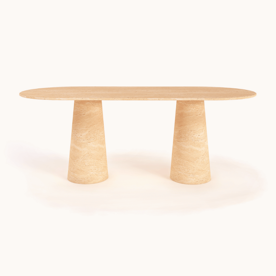 The Harmony Oval Travertine Dining Table from Travertable is a minimalist beige table featuring an oval top and two conical pedestal legs. Its smooth, natural wood texture mirrors the chic elegance of travertine, set against a plain white background.