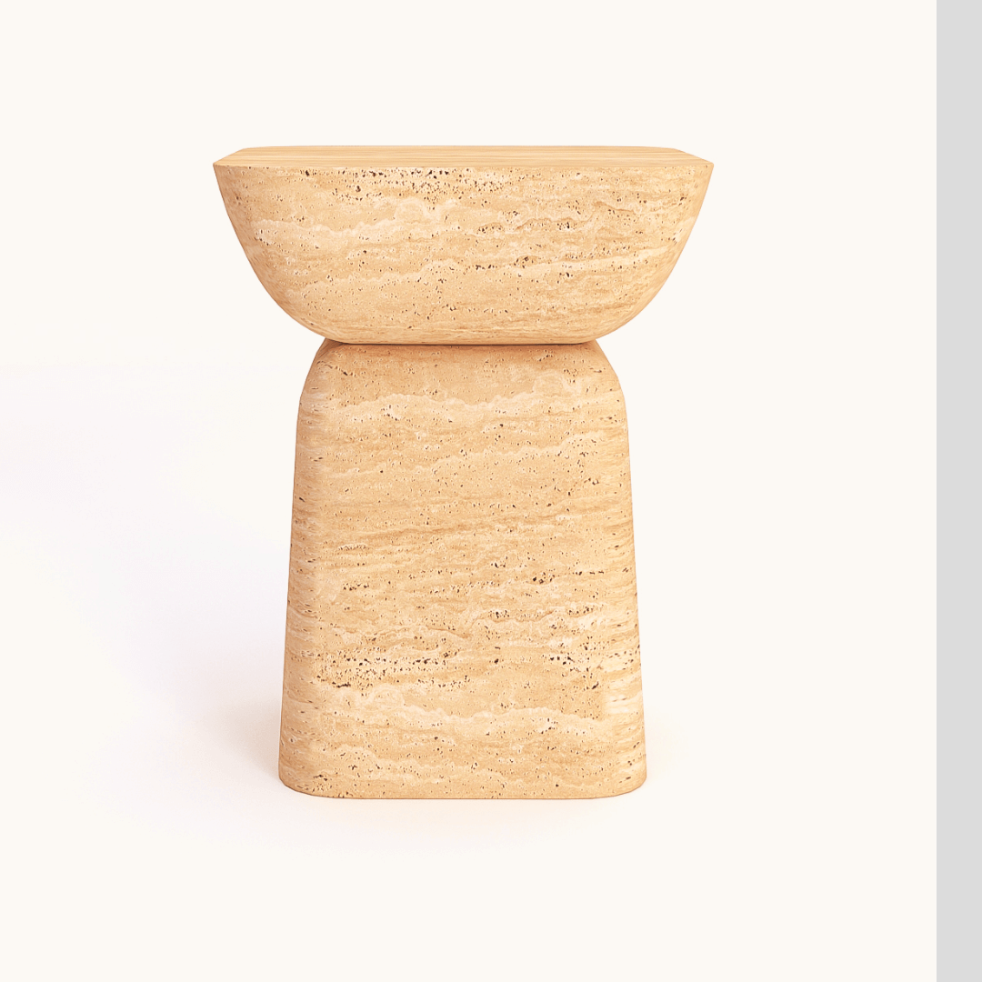 The Modern Minimalist Travertine Side Table by Travertable is a tan, textured stone accent with a bowl-shaped seat and trapezoidal base, placed against a plain, light background.