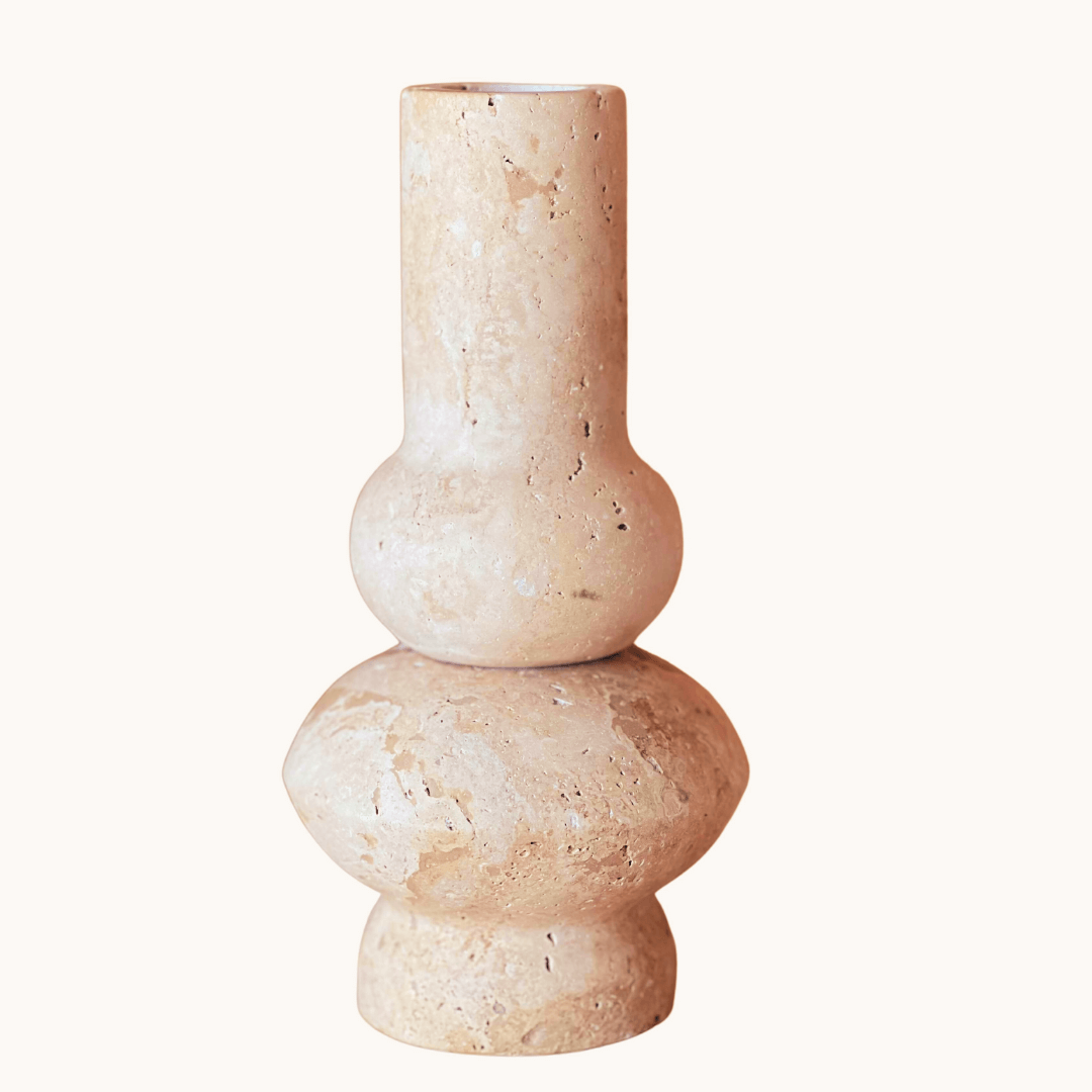 The Travertable Minimalist Beige Travertine Vase features a unique sculptural design with a narrow cylindrical top, rounded middle, and wider base in textured beige ceramic, standing out artistically against a plain white background.
