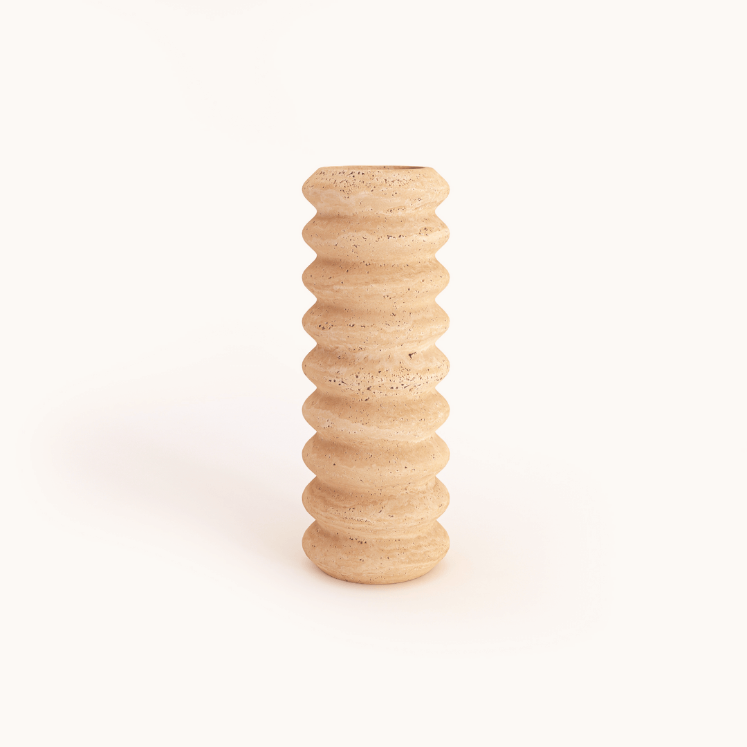 The Natural Beauty Oval Travertine Vase by Travertable is a tall, beige ceramic vase featuring a textured, wavy pattern against a light background. Its subtly speckled surface enhances its natural esthetic.