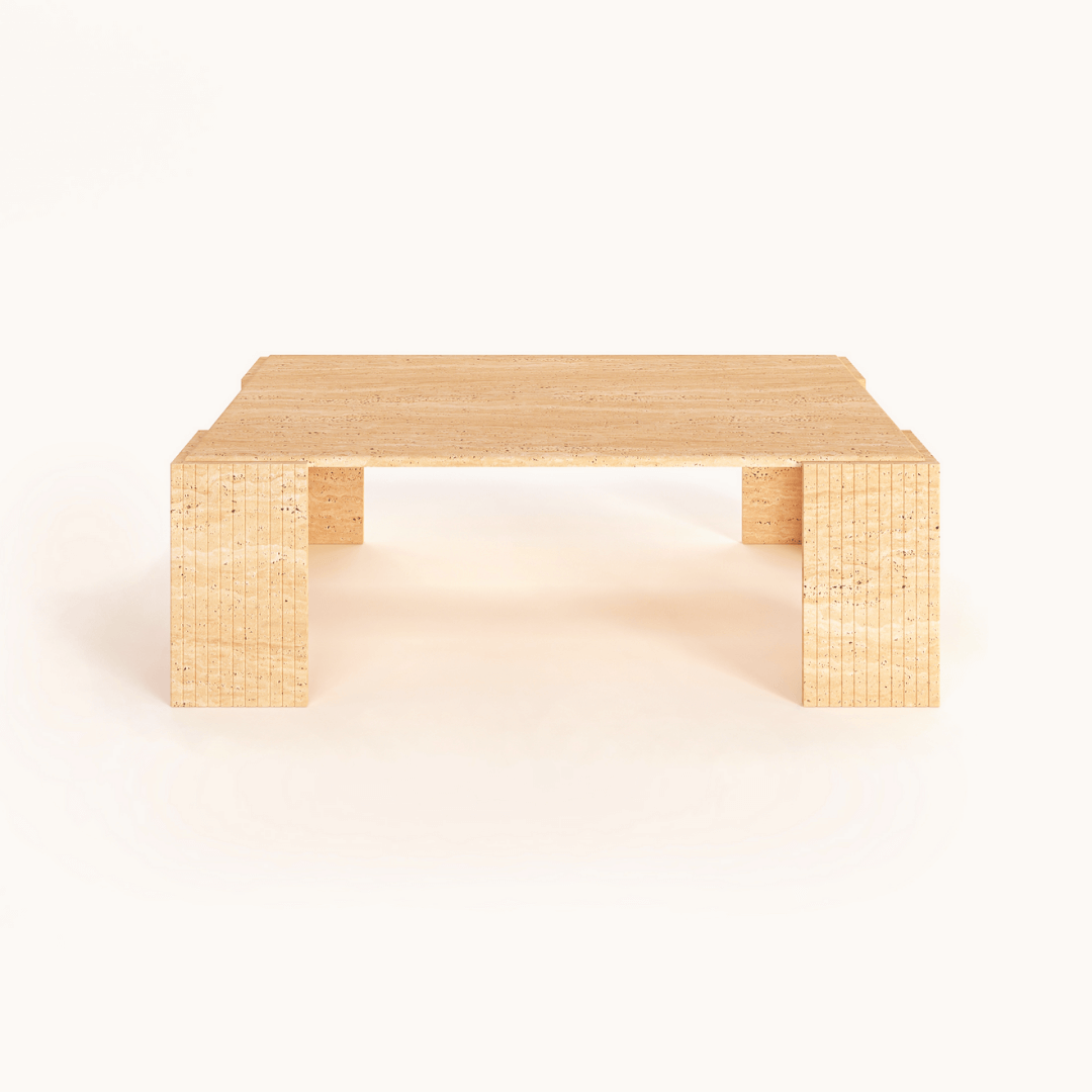 The Modern Rustic Travertine Coffee Table by Travertable, featuring block-style legs and a minimalist design, balances raw texture with refined form and showcases its natural beauty against a plain white background.