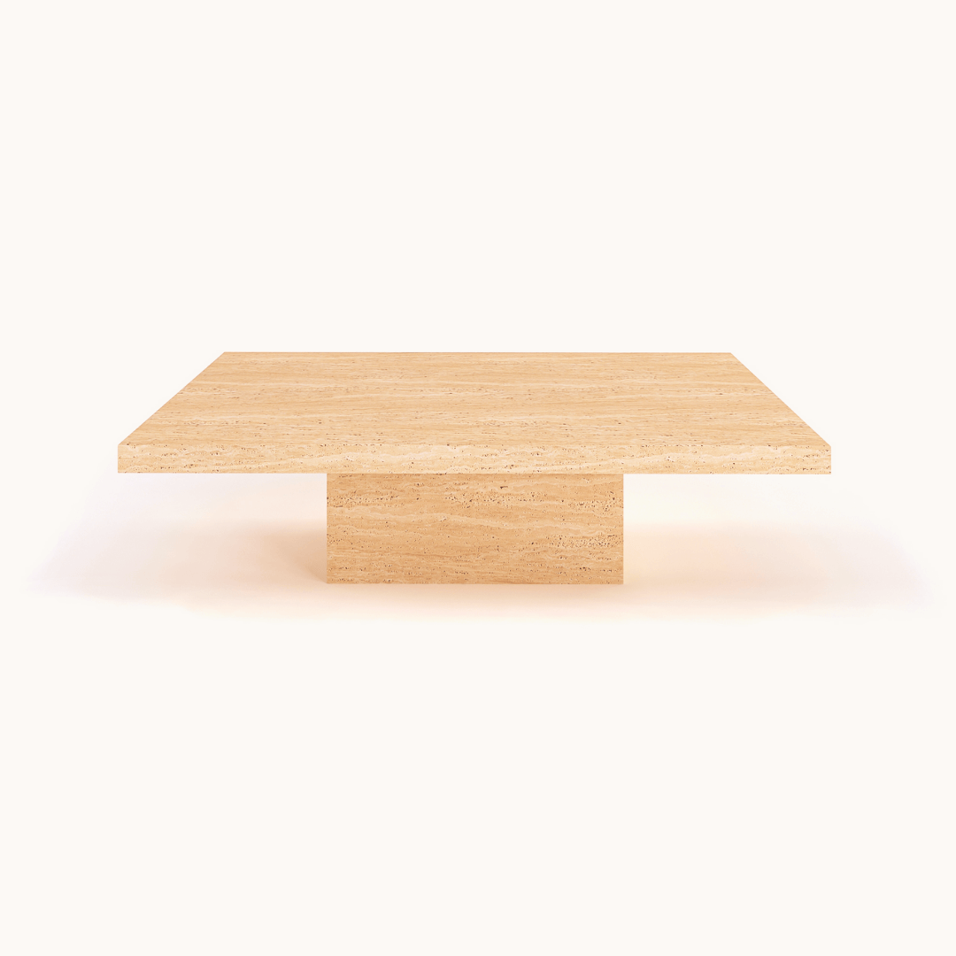 The Minimalist Travertine Accent Coffee Table by Travertable features a square beige top and solid pedestal base, epitomizing luxury interior design. Its natural stone design elegantly contrasts against a crisp white background.