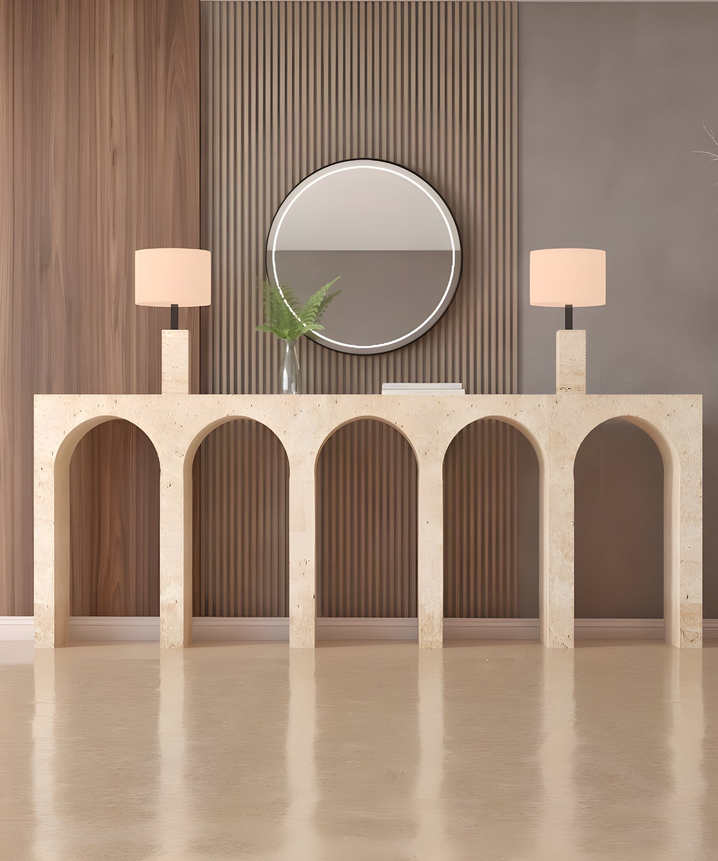 The TRAVERTABLE Travertine Console Table with Five Arches, topped with modern lamps, a round mirror, book, and glass vase of green leaves, brings understated luxury to wood paneling and gray accents.