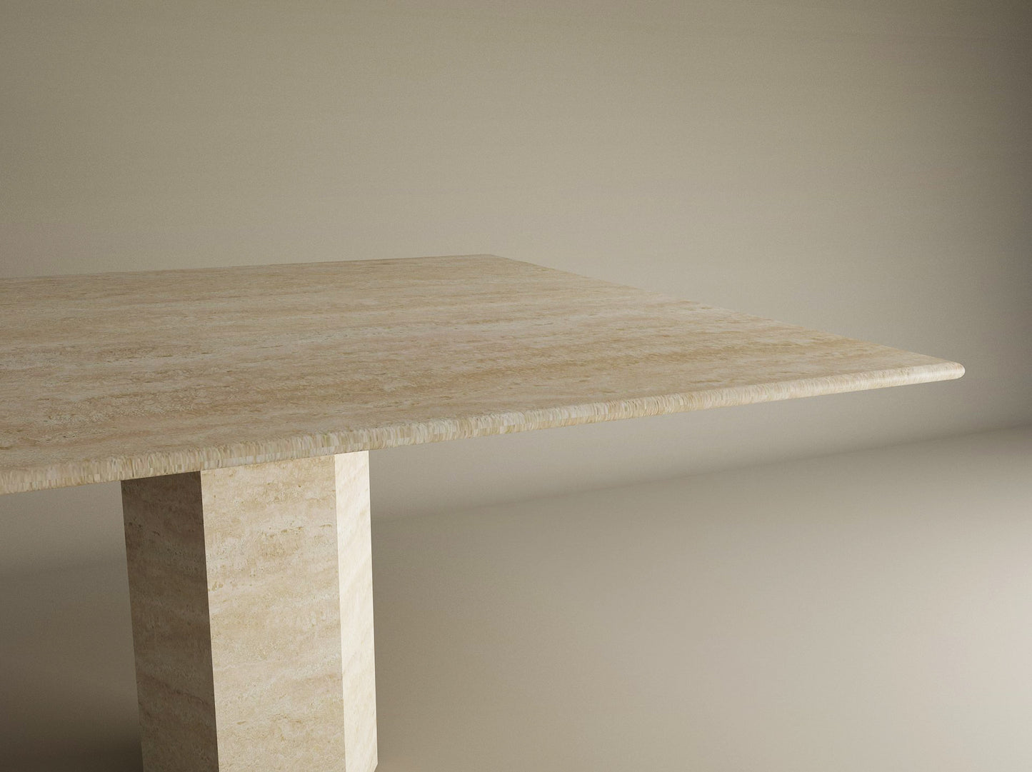 A partial view of the TRAVERTABLE Square Travertine Dining Table with Hexagonal Center Base is shown against a plain, light background, highlighting its beige stone top and geometric pedestal.