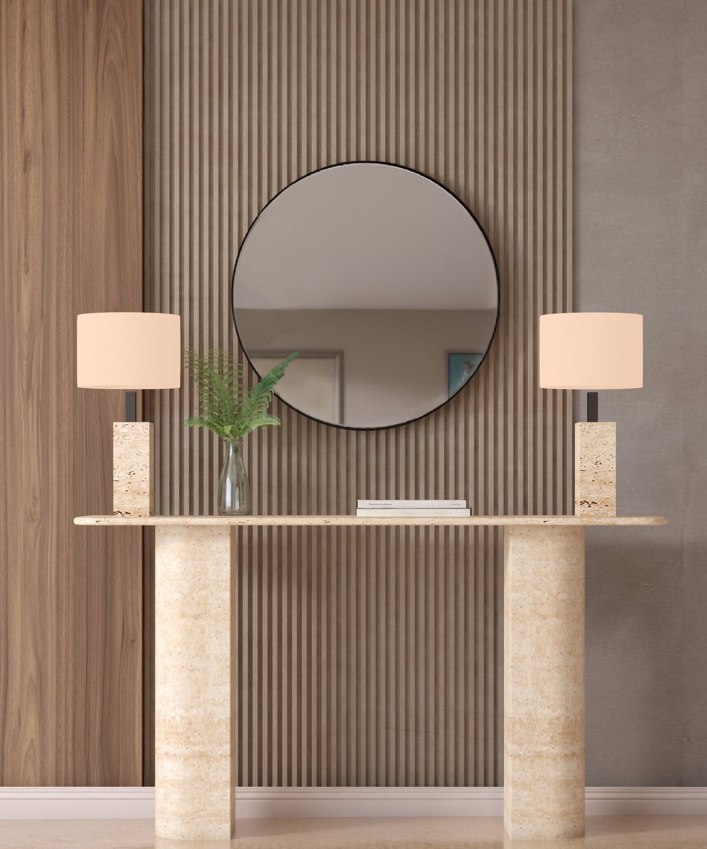 A TRAVERTABLE Rectangular Travertine Console Table with Sloped Pedestal Base, flanked by matching lamps and a glass vase of ferns, sits against a textured wall beneath a round mirror reflecting the room’s neutral decor.