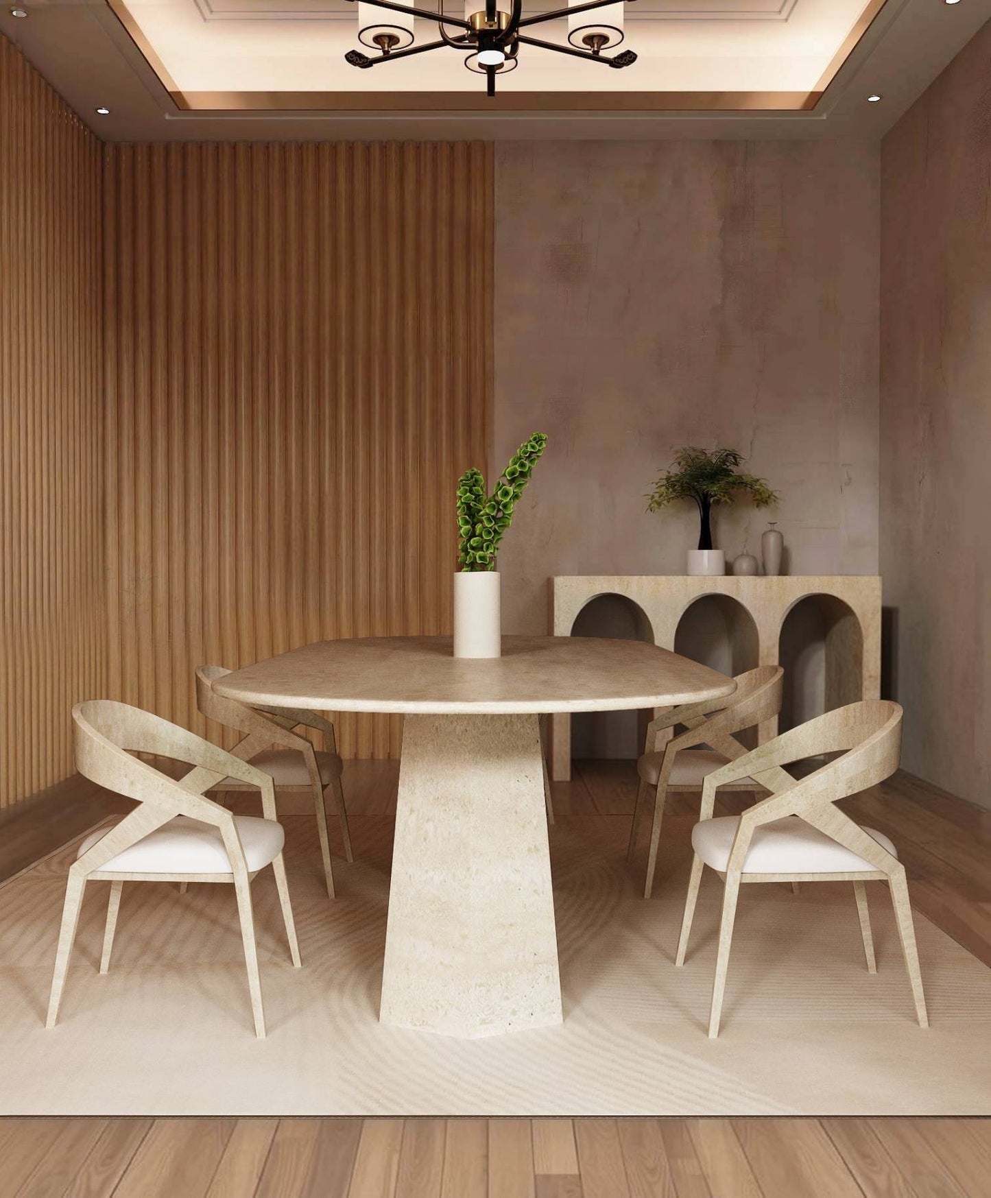 A modern dining room featuring the TRAVERTABLE Oval Travertine Dining Table with a solid stone base, four matching chairs, a light rug, green-leaf vase centerpiece, wood accent wall, and console table with decor against a beige wall.