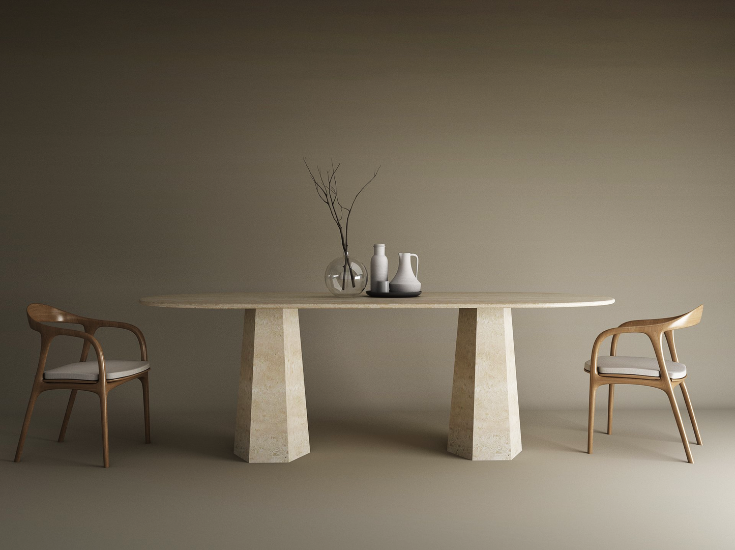 A minimalist dining setup features the TRAVERTABLE Oval Travertine Dining Table with Tapered Round Base, two wooden chairs with white cushions, a vase with dried branches, and two pitchers, all set against a plain beige background.