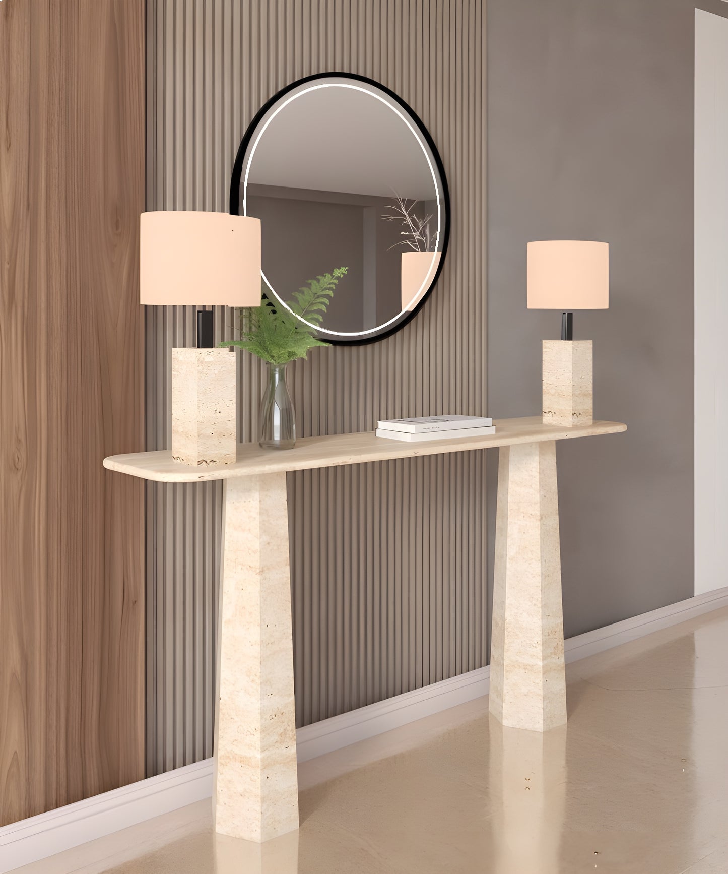 A Rectangular Travertine Console Table with Tapered Round Base by TRAVERTABLE displays two matching lamps, a vase with greenery, and a book. Placed against vertical wall paneling, it sits beneath a round mirror reflecting the room.