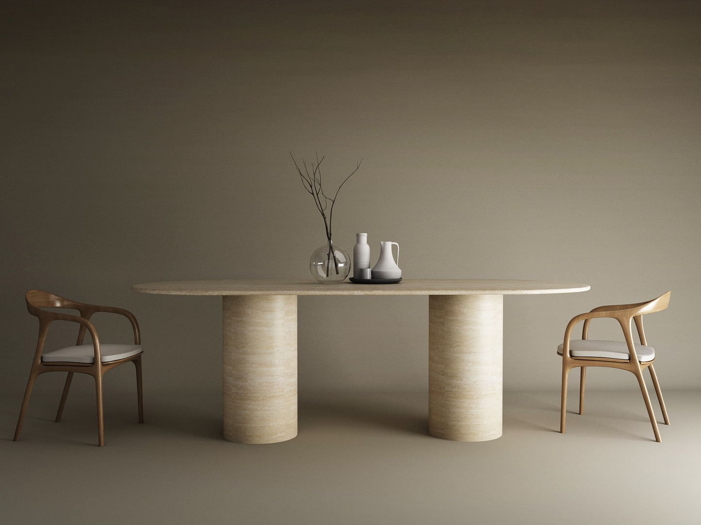 A minimalist dining setup featuring the TRAVERTABLE Oval Travertine Dining Table with Smooth Cylinder Base, two wooden chairs with white cushions, and simple vases—one holding bare branches—set against a plain taupe background.
