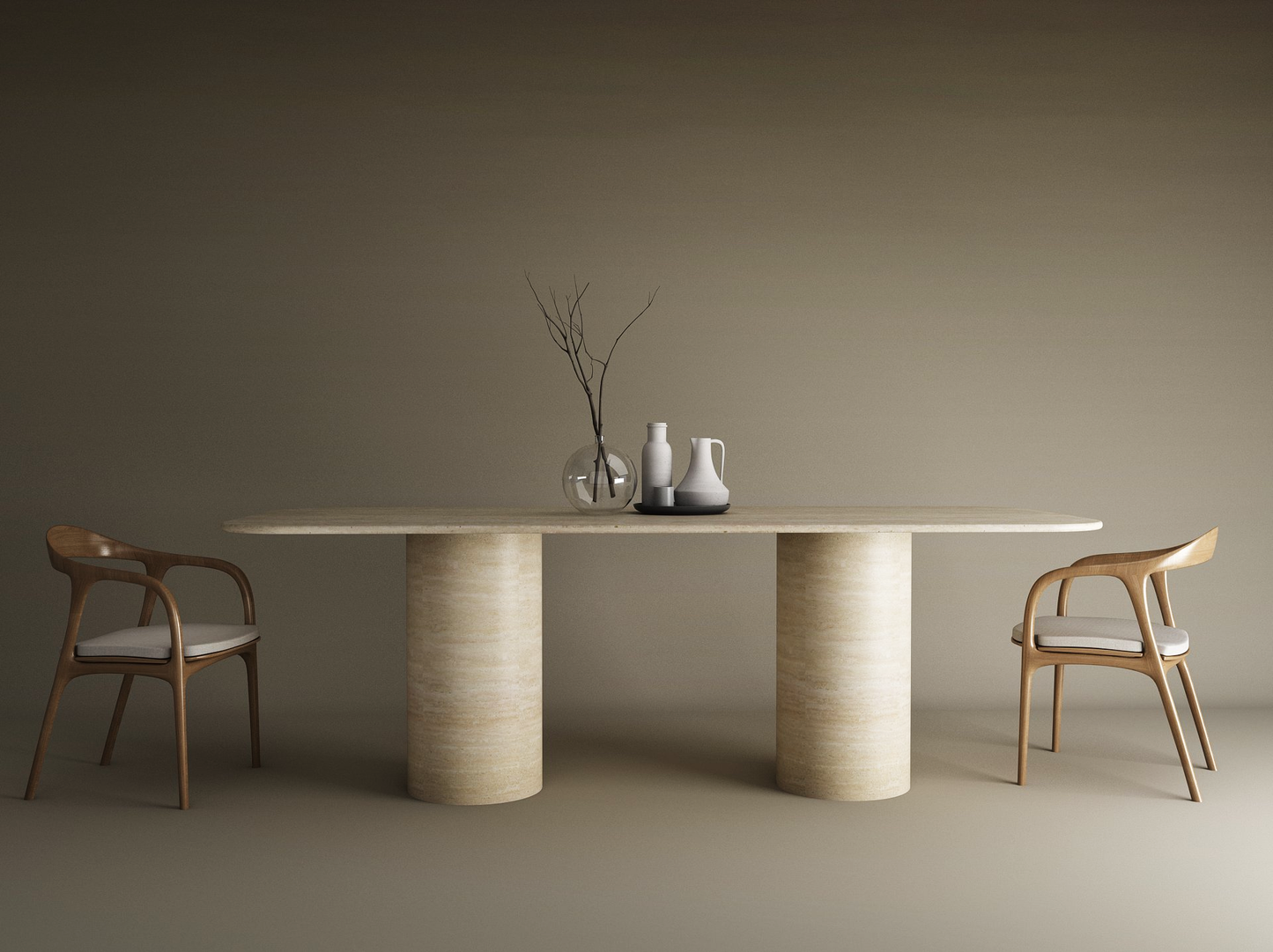 The TRAVERTABLE Rectangular Travertine Dining Table with Cylindrical Base sits between two wooden chairs with white cushions. On the natural stone surface are a clear vase with branches and three ceramic vessels, set against a plain brown wall.