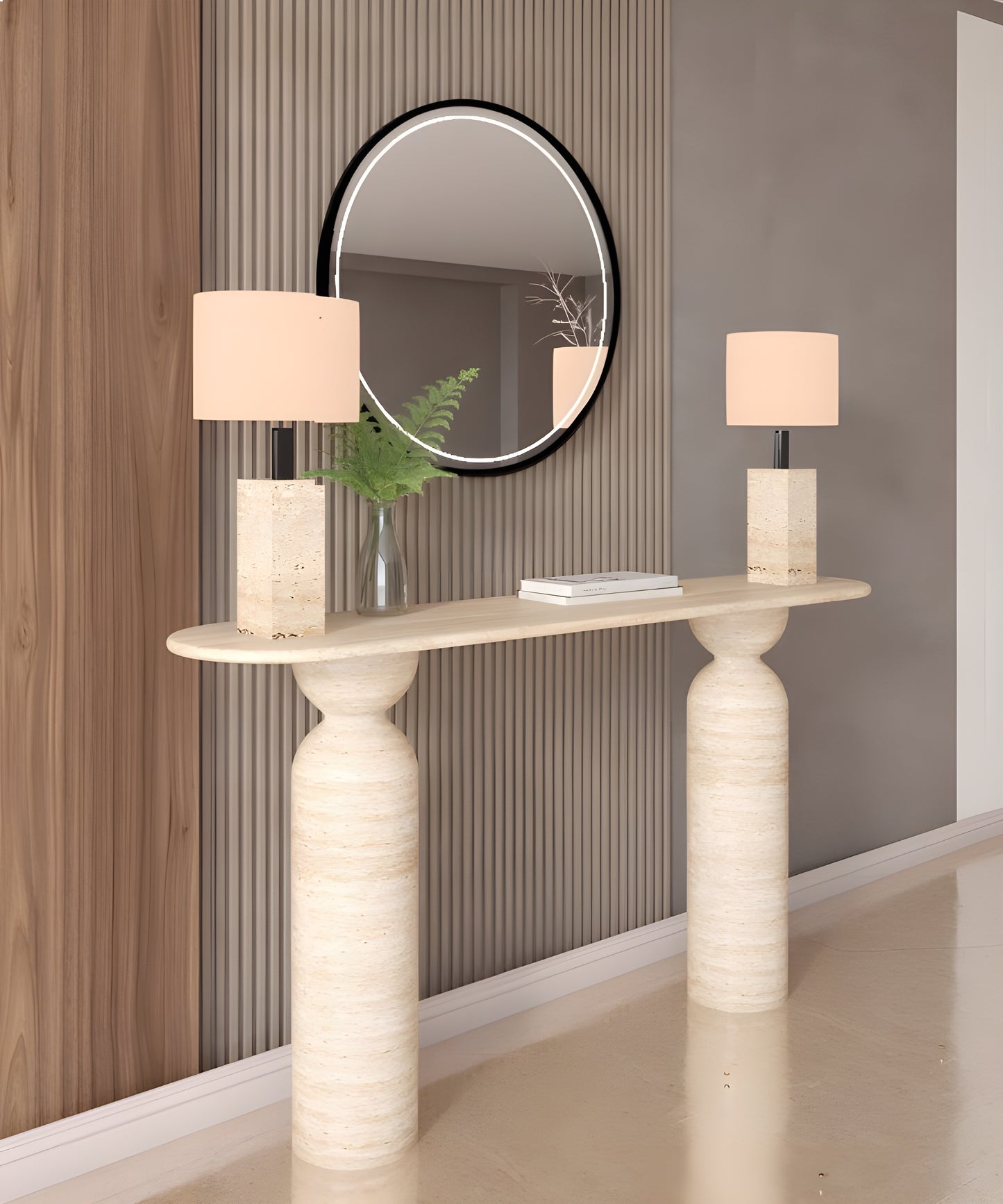 A modern entryway featuring the TRAVERTABLE Ovale Travertine Console Table with a sculptural organic travertine stone base, two beige lamps, a round black-framed mirror, green fern leaves in a glass vase, and vertical wood and taupe wall panels.