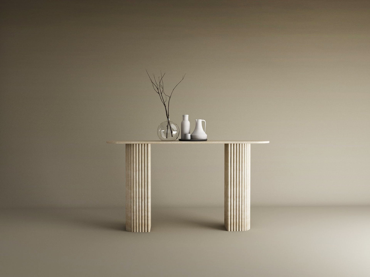 The TRAVERTABLE Ovale Travertine Console Table features a solid, fluted round base and natural stone texture. Against a beige backdrop, three minimalist vases—one with bare branches—adorn its surface in a modern, understated style.