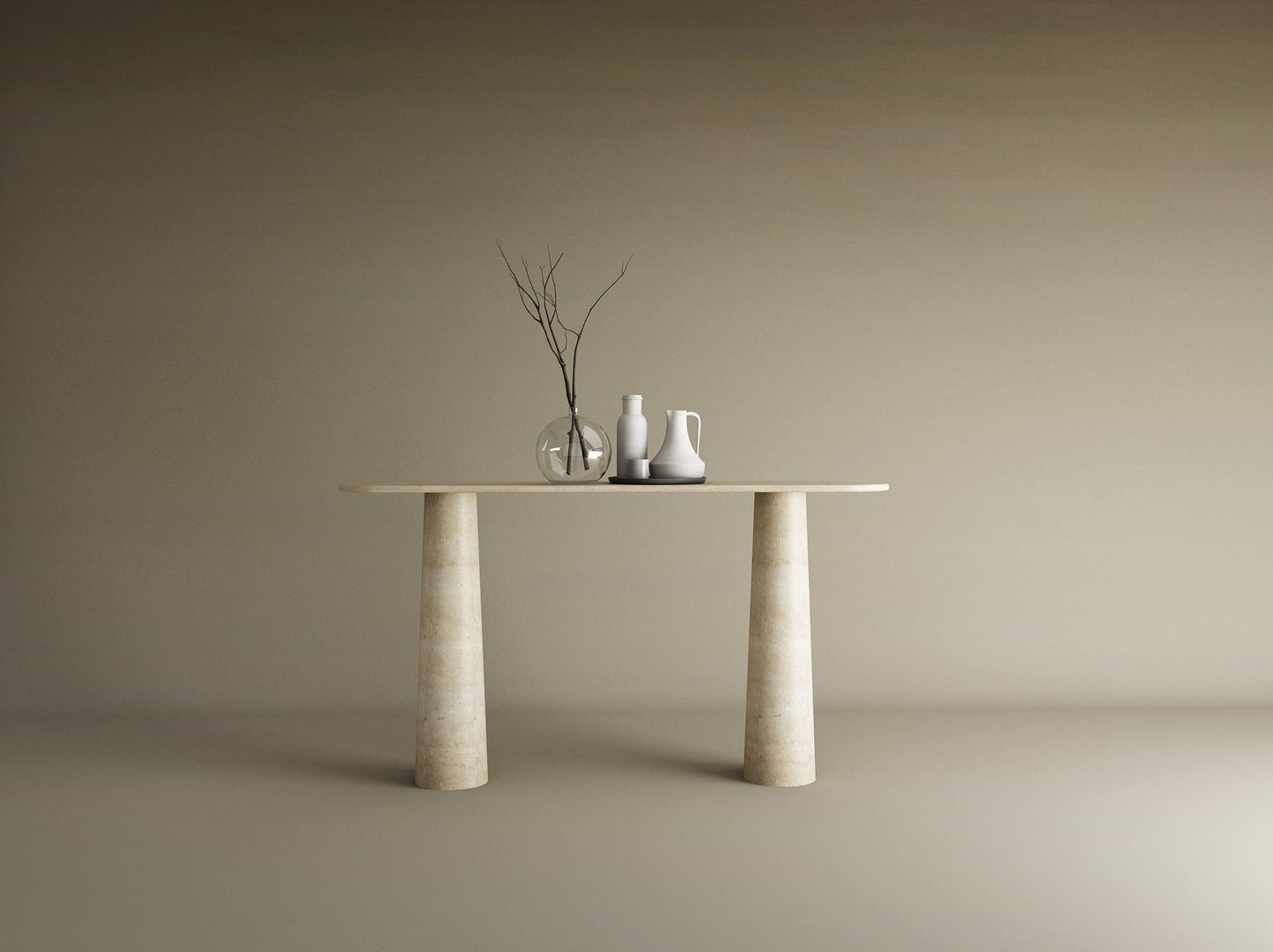 The Ovale Travertine Console Table by TRAVERTABLE features an organic travertine stone top and conical pedestal base. Three ceramic vases—one transparent, two opaque—with bare branches sit against a plain beige background.
