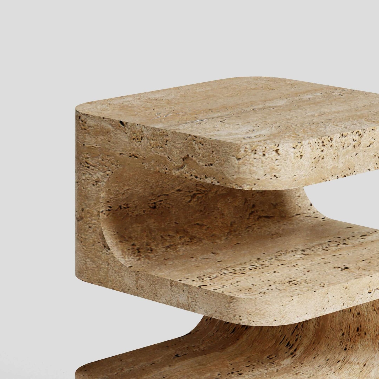 A close-up of the Serenity Block Travertine Table by Travertable reveals its C-shaped design with smooth, rounded edges and a natural stone texture against a plain light gray background. This elegant table melds functionality with timeless style.