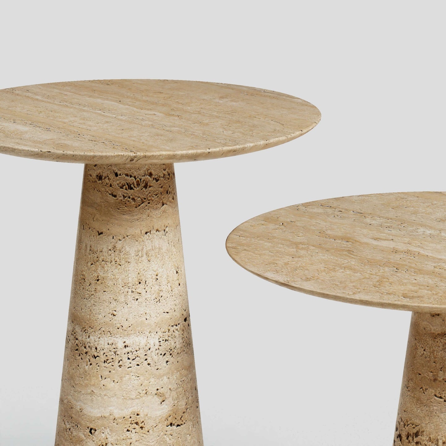 Travertables Twin Pillars Travertine Side Table Set exudes natural elegance. The set, featuring conical bases and round tops, stands gracefully against a light gray background, highlighting the stones subtle texture and color variations.