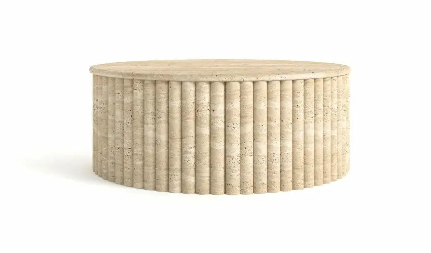 The Alpine Oasis Travertine Coffee Table by Travertable is a round, beige table with a fluted, cylindrical base and smooth top, resembling natural stone. Its vertical ridges and textured design offer a modern look that complements elegant interiors against a plain white backdrop.