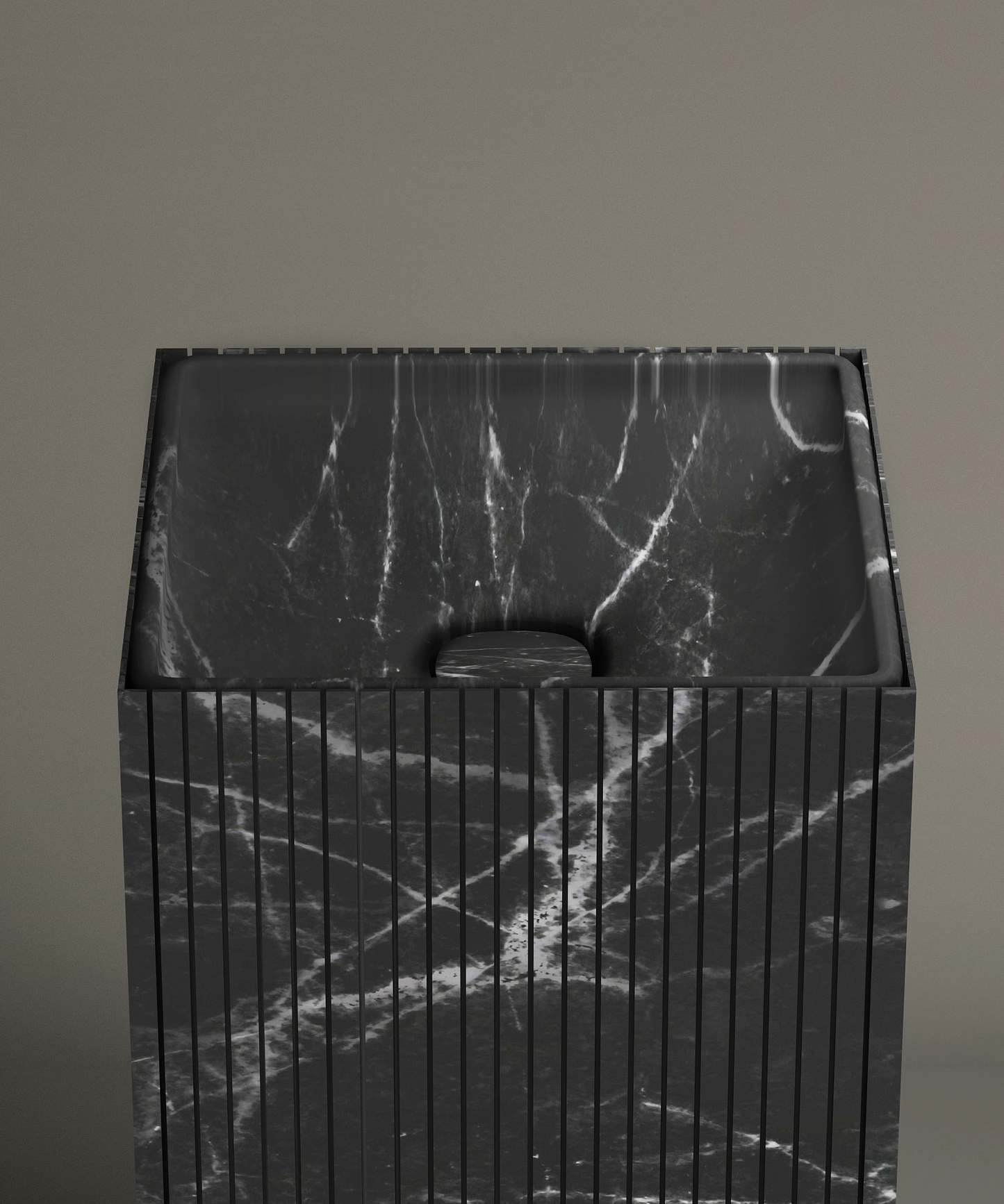The TRAVERTABLE Nero Marquina Square Fluted Marble Pedestal Vanity Sink, featuring black marble with white veining and vertical grooves, stands against a taupe bathroom wall. Its drain cover matches the sink’s distinctive marble pattern.