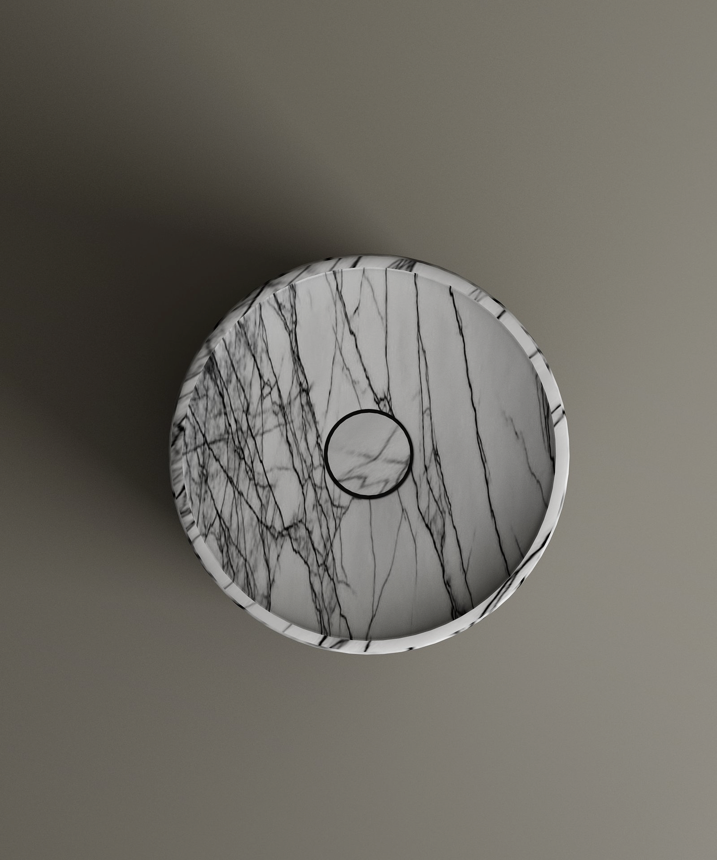 The Lilac Round Marble Pedestal Vanity Sink by TRAVERTABLE, crafted from white natural stone with dark gray veining, is displayed from above on a matte gray surface. The centered drain and sculptural form cast a subtle leftward shadow.