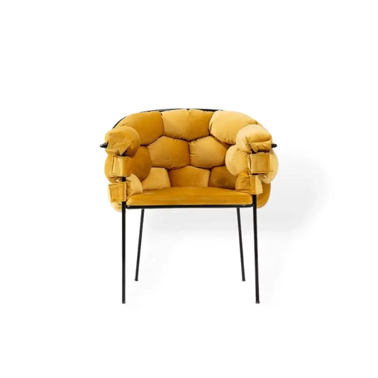 The Luxurious Mustard Yellow Armchair by Travertable boasts a plush, bubble-like design with premium upholstery on its cushioned, tufted backrest and armrests. It stands elegantly on slender black metal legs against a white background.