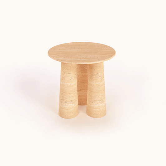 The Elysian Triple Cone Travertine Round Table by Travertable showcases a minimalist design with a smooth, light brown finish and three cylindrical legs, standing elegantly against a plain, light background.