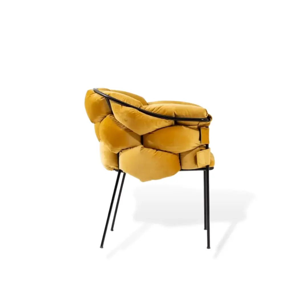 The Travertable Luxurious Mustard Yellow Armchair features a modern, artistic design with premium upholstery. Its soft, rounded cushions and sleek black metal legs create a cloud-like appearance against a white background.