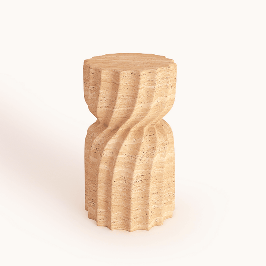 The Natural Beauty Travertine Stone Side Table by Travertable is a beige piece with a cylindrical, wavy design resembling a sand sculpture. It adds an artistic touch to any room and stands out against plain backgrounds, making it ideal for modern and creative spaces.