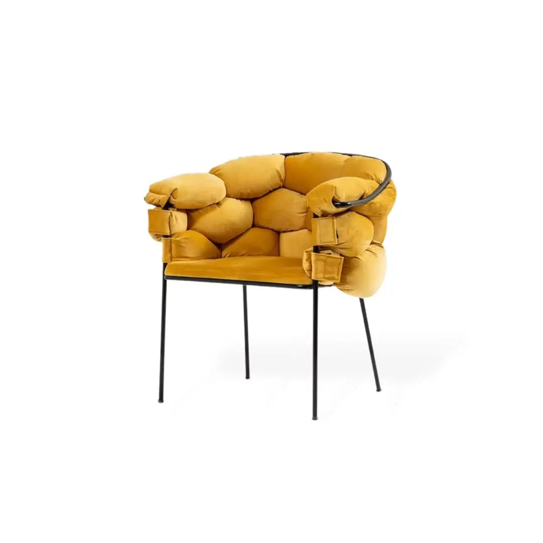 The Luxurious Mustard Yellow Armchair by Travertable features a modern design with rounded cushioned backrest and arms, supported by sleek black metal legs. Its premium upholstery offers comfort and an artistic flair to any space.