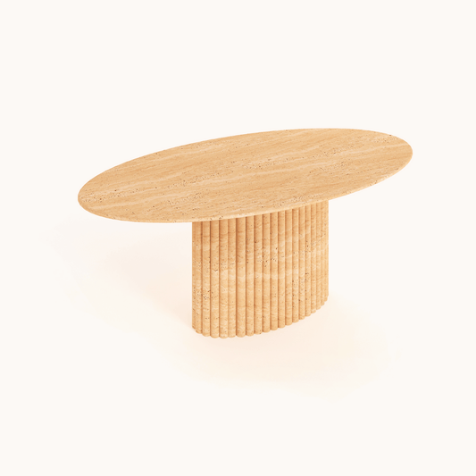 The Elysian Travertine Feast Table by Travertable has an oval wooden top with a smooth finish and a ribbed pedestal base made of vertical slats. Its light natural finish, set against a plain white background, beautifully highlights the wood grain.