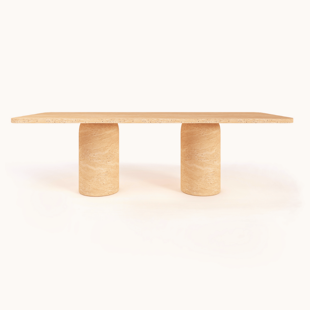 The Monarch Travertine Dining Table by Travertable showcases a rectangular design with a light wood finish and two cylindrical legs. Its minimalist, contemporary style emphasizes clean lines and a smooth surface for a modern, elegant look against a plain white background.