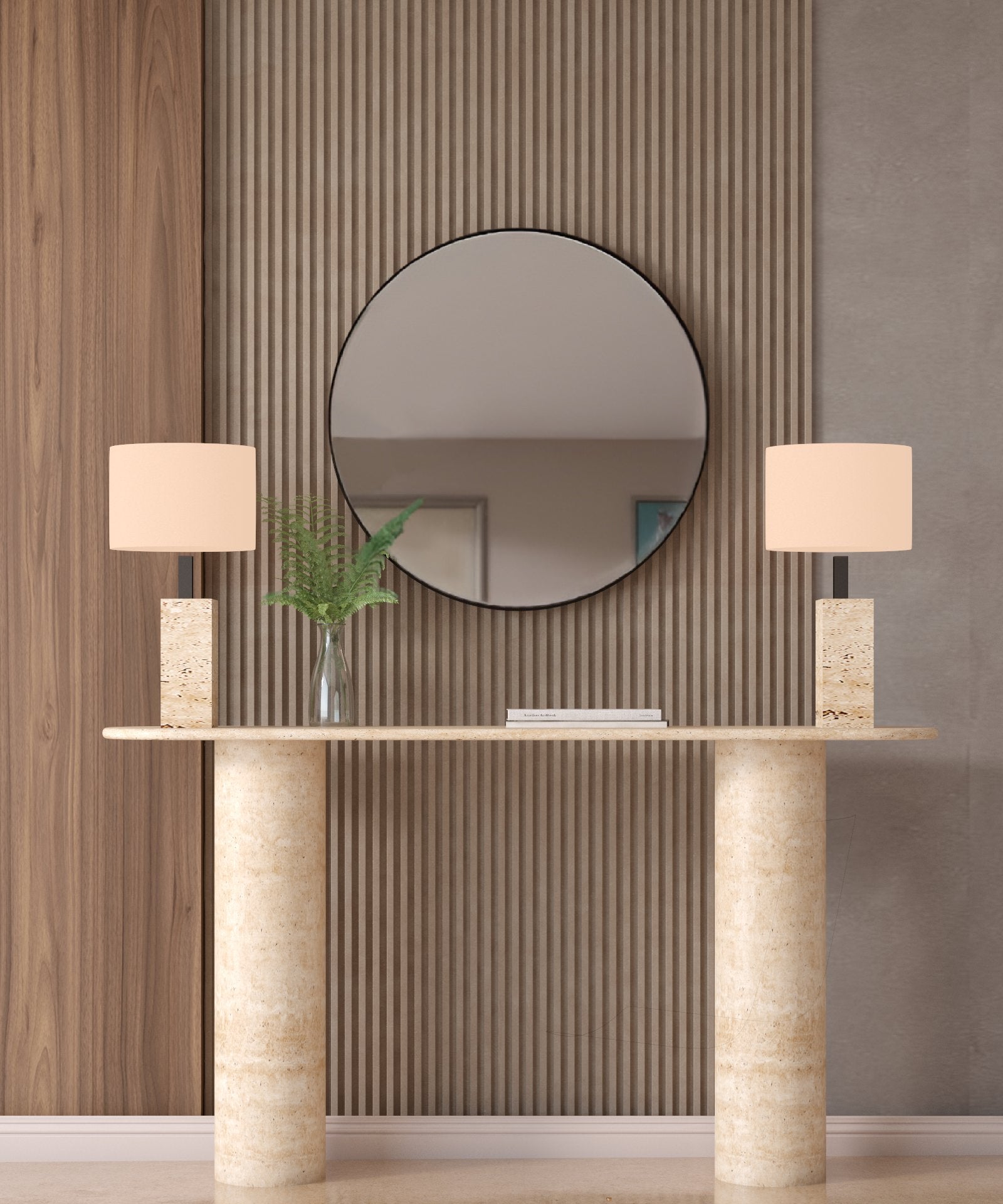 A round mirror hangs above the TRAVERTABLE Ovale Travertine Console Table with a smooth pure stone base, flanked by two stone lamps and a vase of green fern leaves against neutral vertical wood and textured panels.