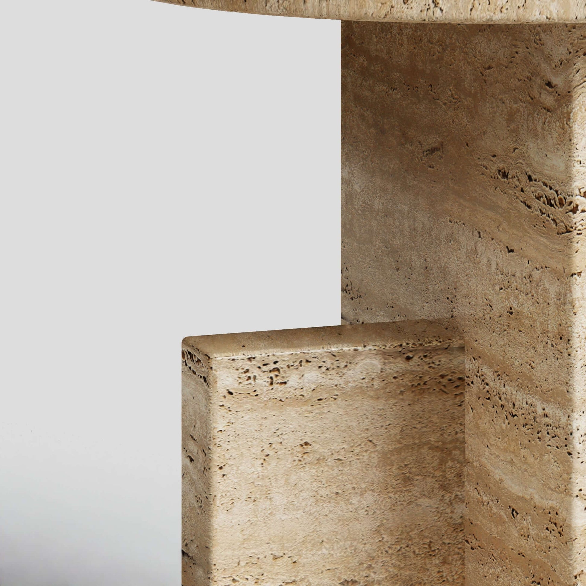 Close-up of the Travertine Scepter Side Table by Travertable, showcasing a geometric and modern design with a light beige, textured honed travertine surface. The unique architectural form features clean lines and right angles that highlight its natural patterns against a neutral background.