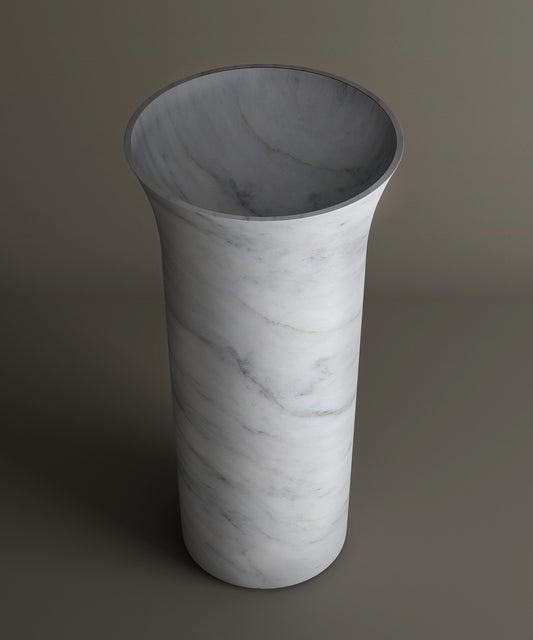 The TRAVERTABLE Carrara Marble Cylinder Pedestal Vanity Sink features a tall, cylindrical shape with a flared opening and subtle gray veining, evoking the timeless beauty of high-end marble bathroom sinks.