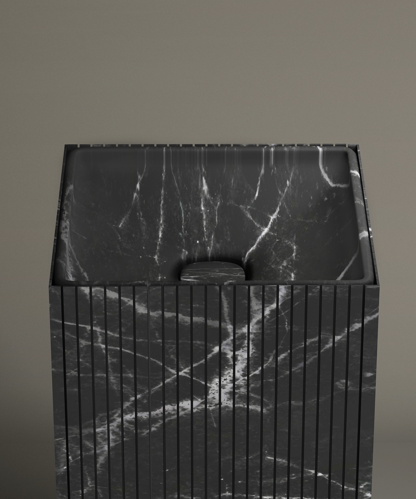 The TRAVERTABLE Nero Marquina Square Fluted Marble Pedestal Vanity Sink, featuring black marble with white veining and vertical grooves, stands against a taupe bathroom wall. Its drain cover matches the sink’s distinctive marble pattern.