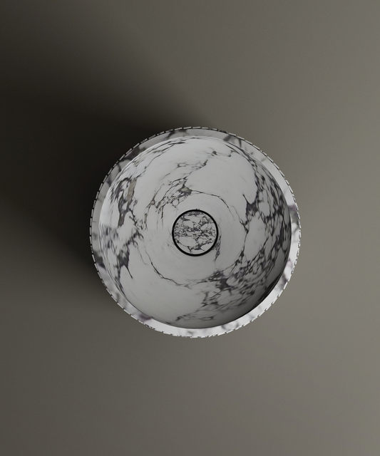 A top-down view shows the TRAVERTABLE Calacatta Round Fluted Marble Pedestal Vanity Sink, featuring white stone with elegant gray veining and a modern design, resting on a smooth gray surface with a subtle left-cast shadow.